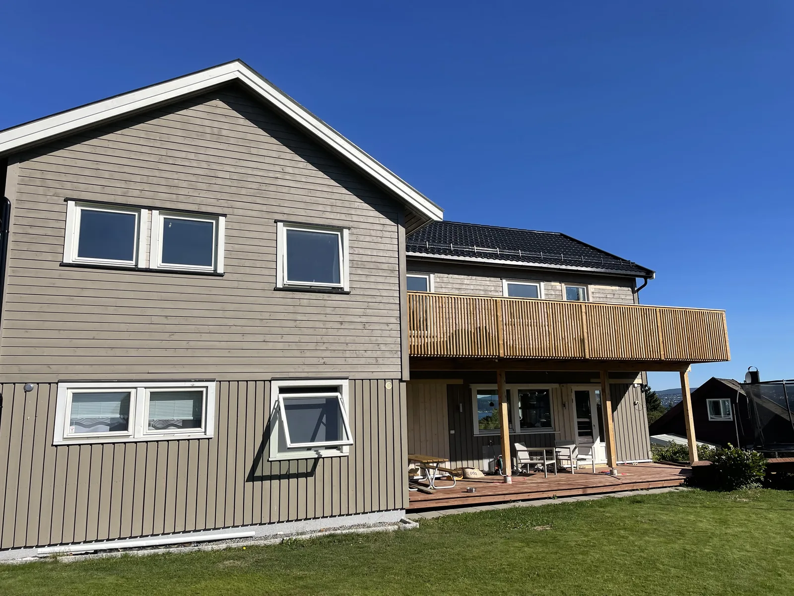 Ferdig påbygg på enebolig med ny trekledning, terrasse på bakkeplan og balkong med spilerekkverk