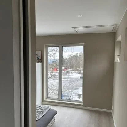 Ferdig oppusset rom med nytt gulv, malte vegger og stort vindu mot hagen